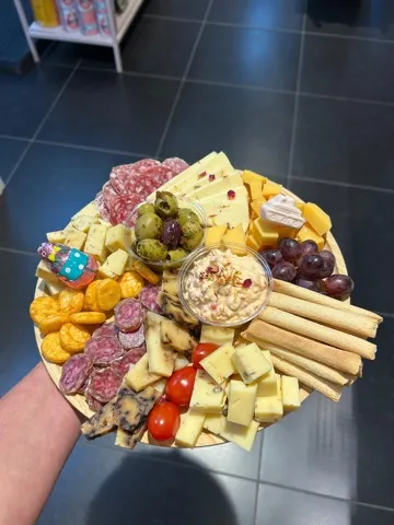Borrelplank voor 4 personen: ronde plank met kaas, worst, olijven, dip, soepstengels en tomaatjes