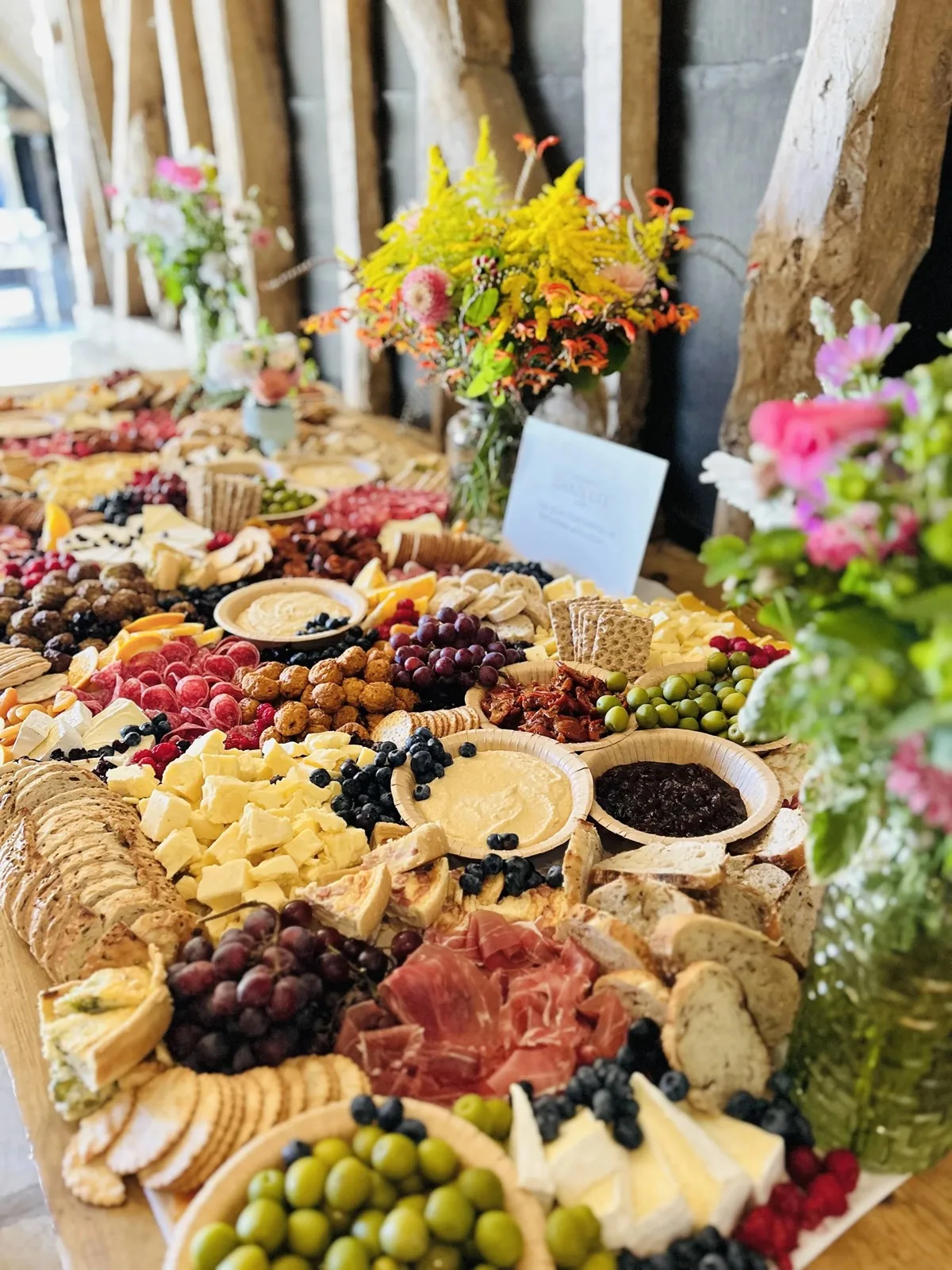 Rijk gevulde kaastafel op locatie: planken met kazen, vlees, fruit, dips en brood